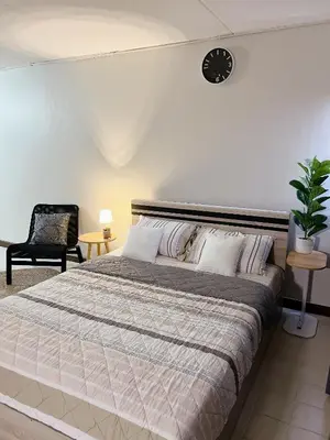 a bedroom with a large bed and a clock on the wall at Condo Popular T4 Impact Muangthong by Tide in Pak Kret