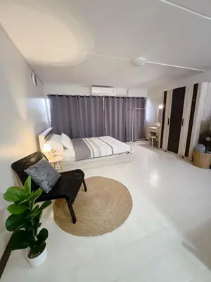 a bedroom with a bed and a chair and a table at Condo Popular T4 Impact Muangthong by Tide in Pak Kret