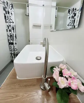 a bathroom with a sink and a faucet and flowers at Condo Popular T4 Impact Muangthong by Tide in Pak Kret
