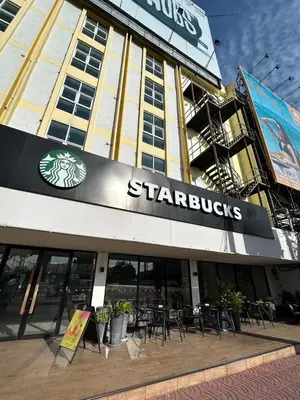a starbucks building with tables and chairs in front of it at The Quarter Hualamphong by UHG in Bangkok