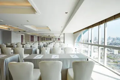 a room with white tables and chairs and a large window at The Quarter Hualamphong by UHG in Bangkok