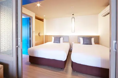 two beds in a small room with a door at The Quarter Hualamphong by UHG in Bangkok