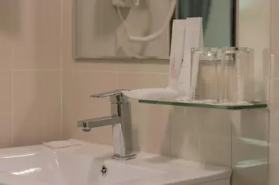 a bathroom with a sink and aaucet and a mirror at Justice Hotel in Bangkok
