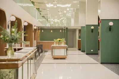 a lobby with green stalls and flowers on a table at Justice Hotel in Bangkok
