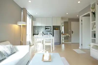 a living room with a white couch and a kitchen at Cinnamon Hotel Bangkok in Bangkok