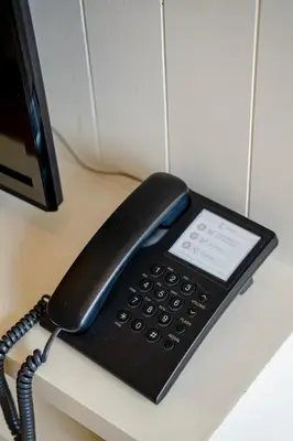 a black phone sitting on top of a desk at Cinnamon Hotel Bangkok in Bangkok