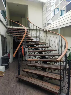 a spiral staircase in a building with wooden steps at Baan Wangderm Hotel in Bangkok
