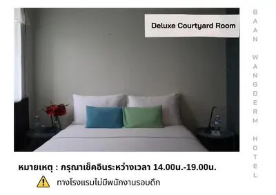 a bedroom with a bed with two pillows on it at Baan Wangderm Hotel in Bangkok
