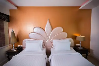 two beds in a room with a flower on the wall at Chillax Resort in Bangkok