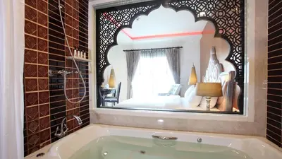a bathroom with a bath tub and a bedroom at Chillax Resort in Bangkok