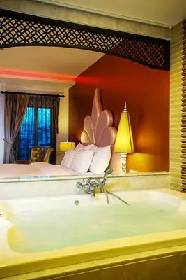 a bathroom with a tub in a room with a bed at Chillax Resort in Bangkok