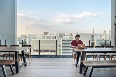 a woman sitting on a table with a laptop on a table at Triple Y Hotel in Bangkok