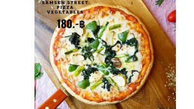 a pizza sitting on top of a wooden table at Samsen Street Hotel in Bangkok