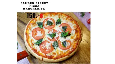a pizza with tomatoes and basil on a wooden table at Samsen Street Hotel in Bangkok