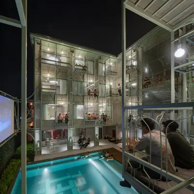 a swimming pool with two people in a building at Samsen Street Hotel in Bangkok
