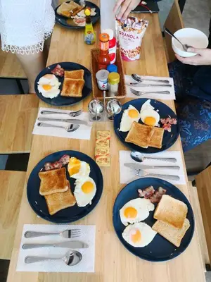 a table topped with plates of eggs and toast at Tropical Summer Hostel in Bangkok