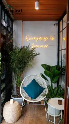 a white wicker chair with a blue pillow on a patio at Tropical Summer Hostel in Bangkok