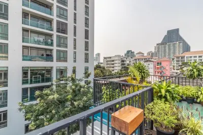 a wooden bench on a balcony with buildings at Every Surawong in Bangkok
