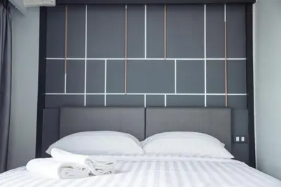 a bed with a black head board and white pillows at Hallton Hotel Bangkok in Bangkok