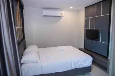 a small bedroom with a bed and a television at Hallton Hotel Bangkok in Bangkok