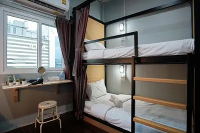 a room with three bunk beds with a desk and a stool at Private Stay Hostel in Bangkok