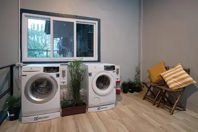 a laundry room with two washing machines and a window at Private Stay Hostel in Bangkok