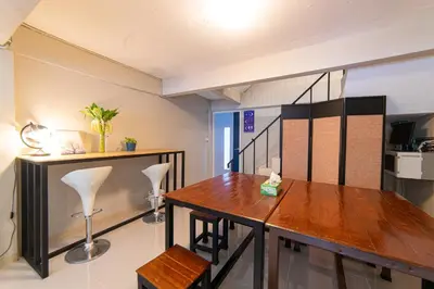 a dining room with a wooden table and chairs at Napa Hostel Samrong Station in Samutprakarn