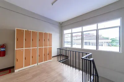 an empty locker room with a staircase and a window at Napa Hostel Samrong Station in Samutprakarn
