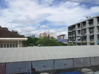 a building with a metal roof in a city at Napa Hostel Samrong Station in Samutprakarn