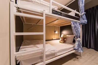 a white bunk bed with a teddy bear sitting on it at Napa Hostel Samrong Station in Samutprakarn