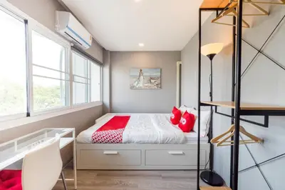 a small bedroom with a bed with red pillows at Bossa House Hostel & Cafe in Bangkok