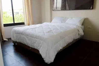 a bed with white sheets and pillows in a bedroom at RQ Bangkok Sukhumvit 107 by Collection O in Samut Prakan