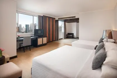 a hotel room with two beds and a desk at The Berkeley Hotel Pratunam in Bangkok