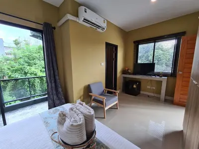 a room with a bed and a chair and a window at The Lantern Suites in Ban Song Hong