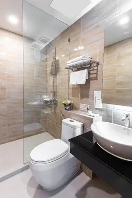 a bathroom with a toilet and a sink at Leela Orchid Hotel in Bangkok