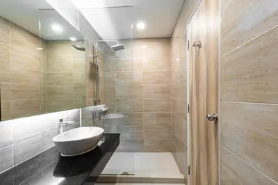 a bathroom with a white sink and a shower at Leela Orchid Hotel in Bangkok
