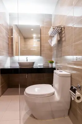 a bathroom with a white toilet and a sink at Leela Orchid Hotel in Bangkok