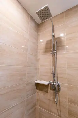 a shower stall in a bathroom with wooden walls at Leela Orchid Hotel in Bangkok