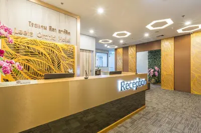 an office lobby with a reception desk and flowers at Leela Orchid Hotel in Bangkok