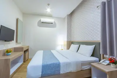 a hotel room with a bed and a tv at Leela Orchid Hotel in Bangkok