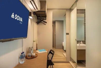 a room with a table and a tv on a wall at SOVA Hotel Bangkok in Bangkok