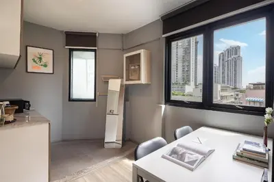a kitchen with a window and a table with chairs at SOVA Hotel Bangkok in Bangkok