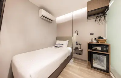 a small bedroom with a bed and a fireplace at SOVA Hotel Bangkok in Bangkok