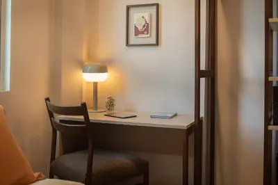 a desk with a lamp and a chair in a room at SOVA Hotel Bangkok in Bangkok