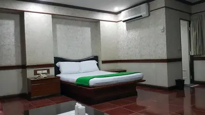 a bedroom with a bed with a green and white pillow at West Wing Mansion in Bangkok