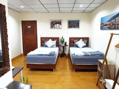 a room with two beds and a table in it at 297 Nature Residence in Bangkok