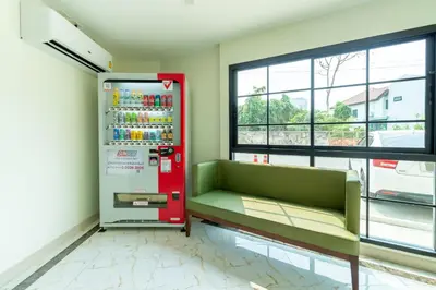 a soda vending machine in a room with a green couch at BeWish Residence Bangphlat in Bangkok