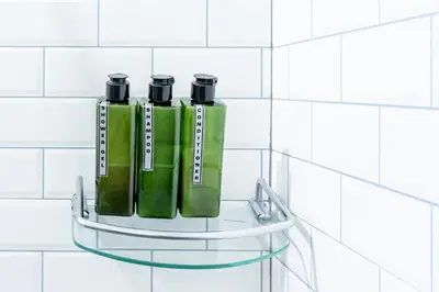 two green bottles on a glass shelf on a white tiled wall at BeWish Residence Bangphlat in Bangkok
