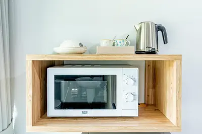 a microwave in a wooden shelf in a kitchen at BeWish Residence Bangphlat in Bangkok