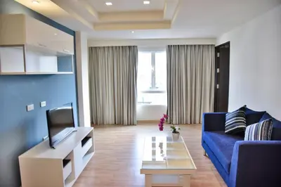 a living room with a blue couch and a tv at The Kaze 34 Hotel and Serviced Residence in Bangkok